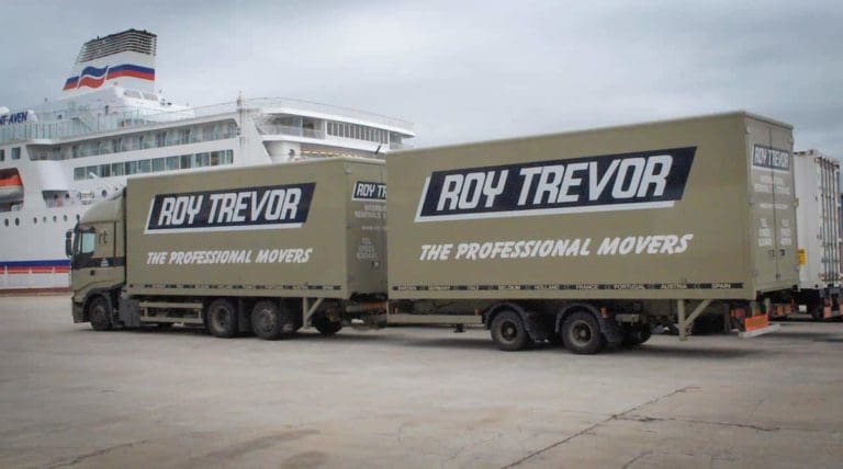 Roy Trevor moving trucks parked beside a large ferry, branded with the slogan “The Professional Movers