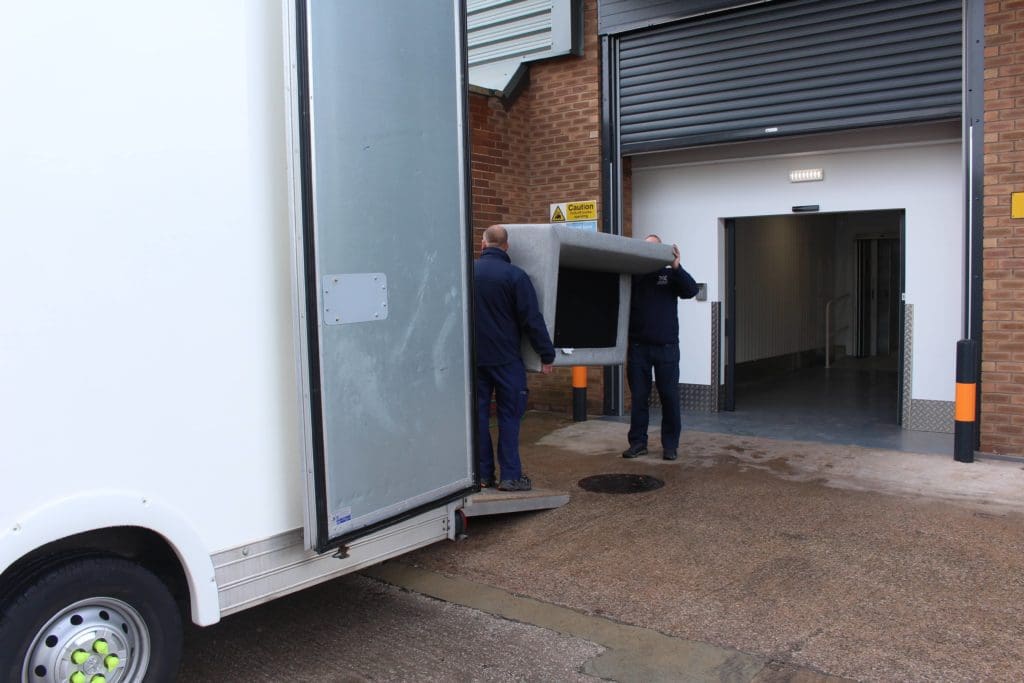 Two men loading a sofa into a self storage unit