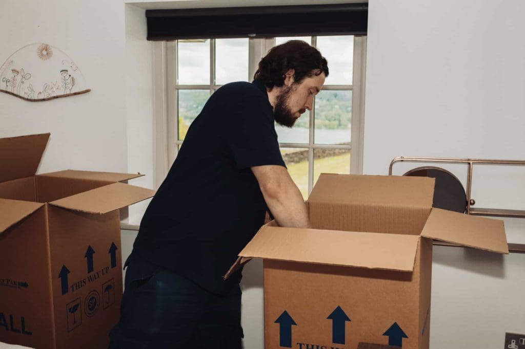 A man with black shirt packing up things in big storage box
